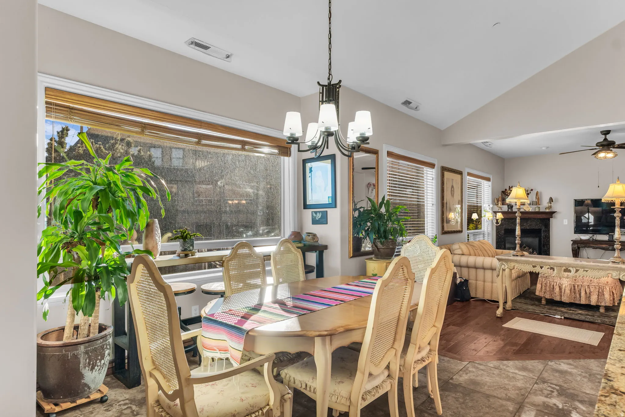 Open-concept floorplan with vaulted ceilings, a dining area featuring a chandelier, and a living area with a fireplace