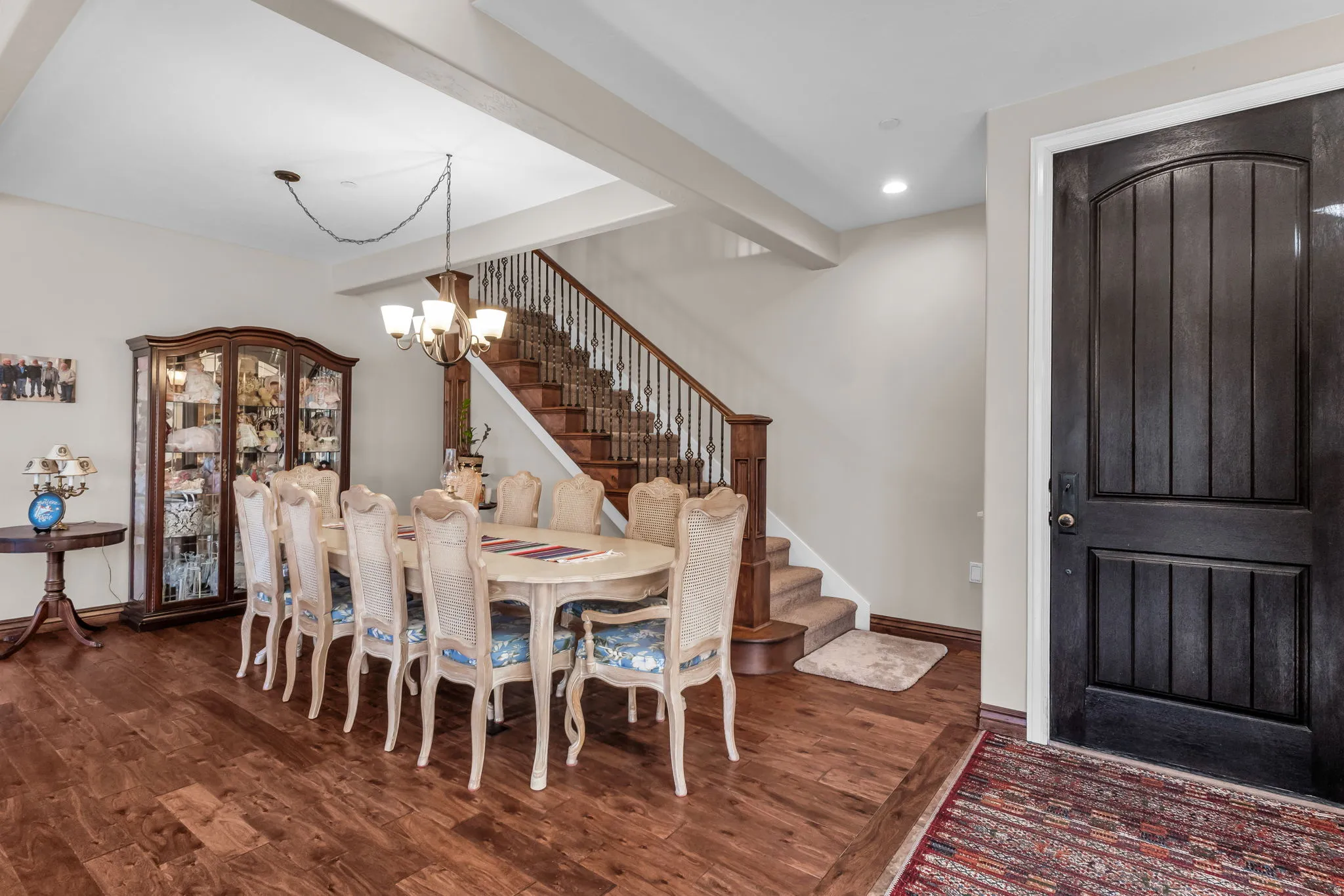 Wood-finish flooring, staircase with wrought iron balusters, recessed lighting, and a dark wood-paneled entry door