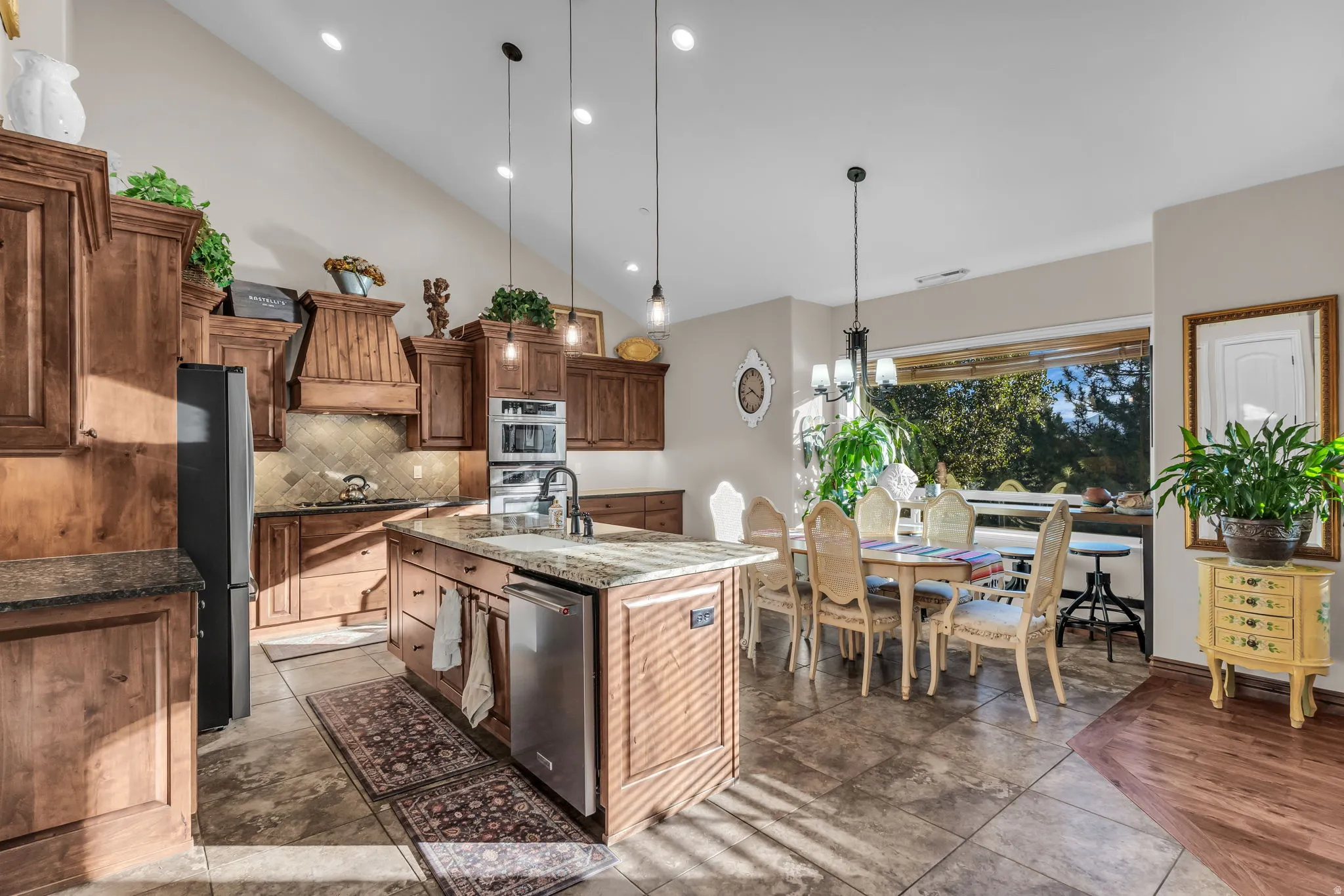 Vaulted ceiling with recessed lighting, wood cabinetry, stone countertops, and a kitchen island with an integrated sink and dishwasher