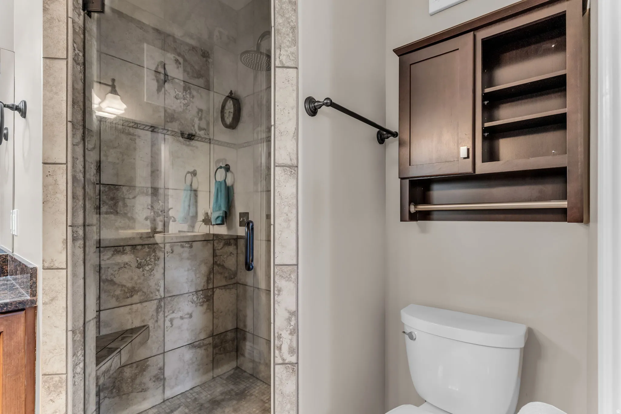 Glass-enclosed shower with a built-in bench, rainfall showerhead, and tile surround