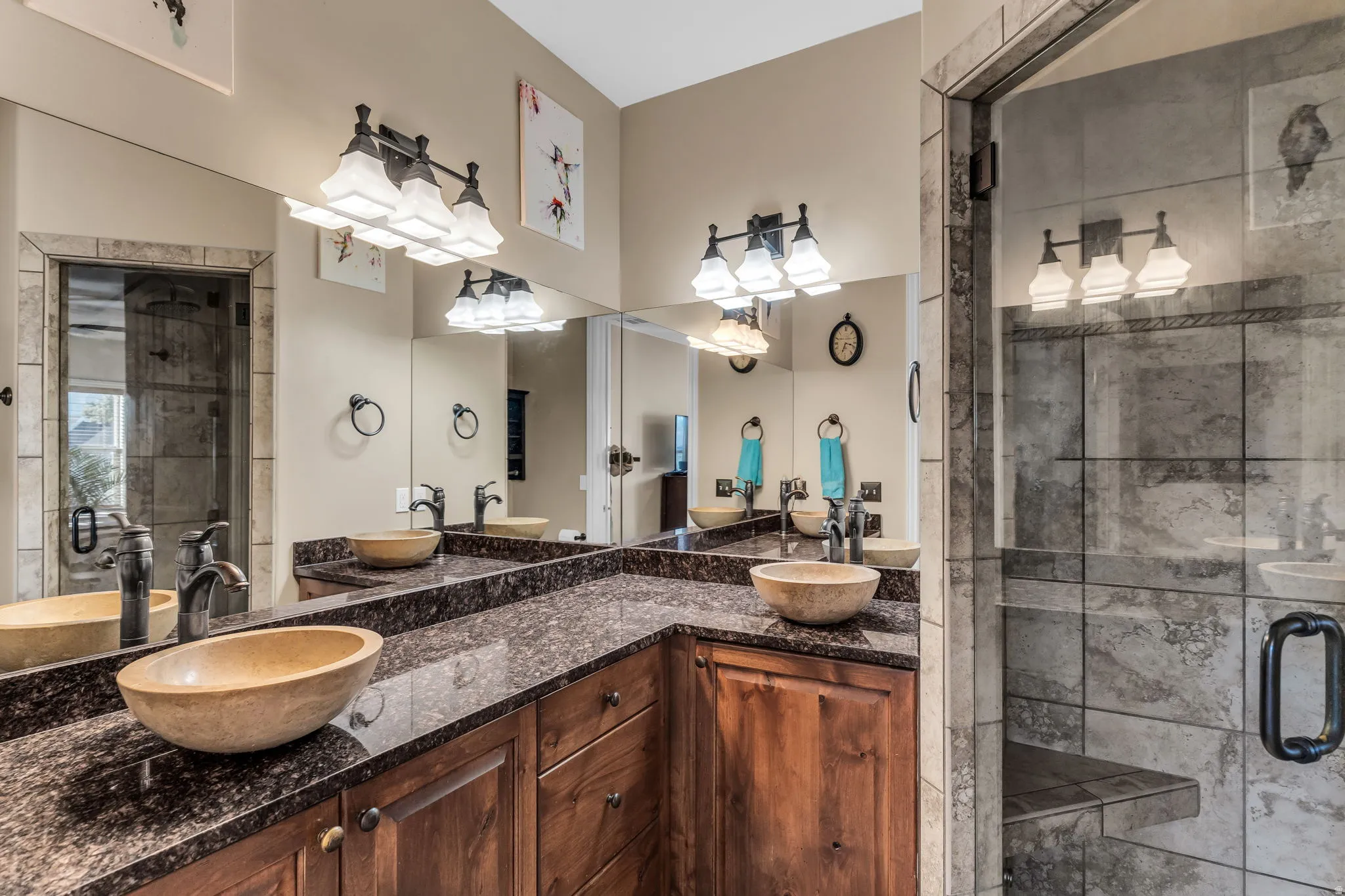 Dual vessel sinks set into a dark granite countertop with wood cabinetry