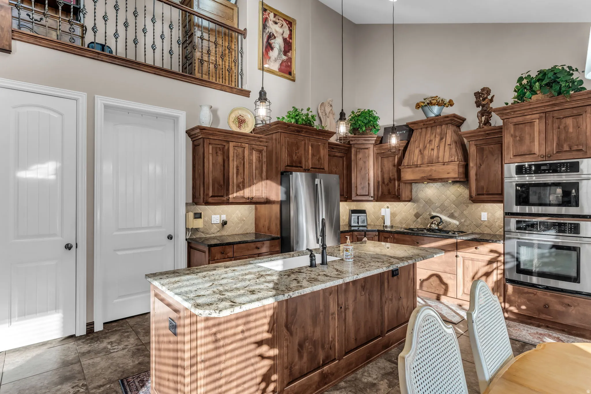 Kitchen featuring rich wood cabinetry, stainless steel appliances, a center island with a sink, and granite countertops