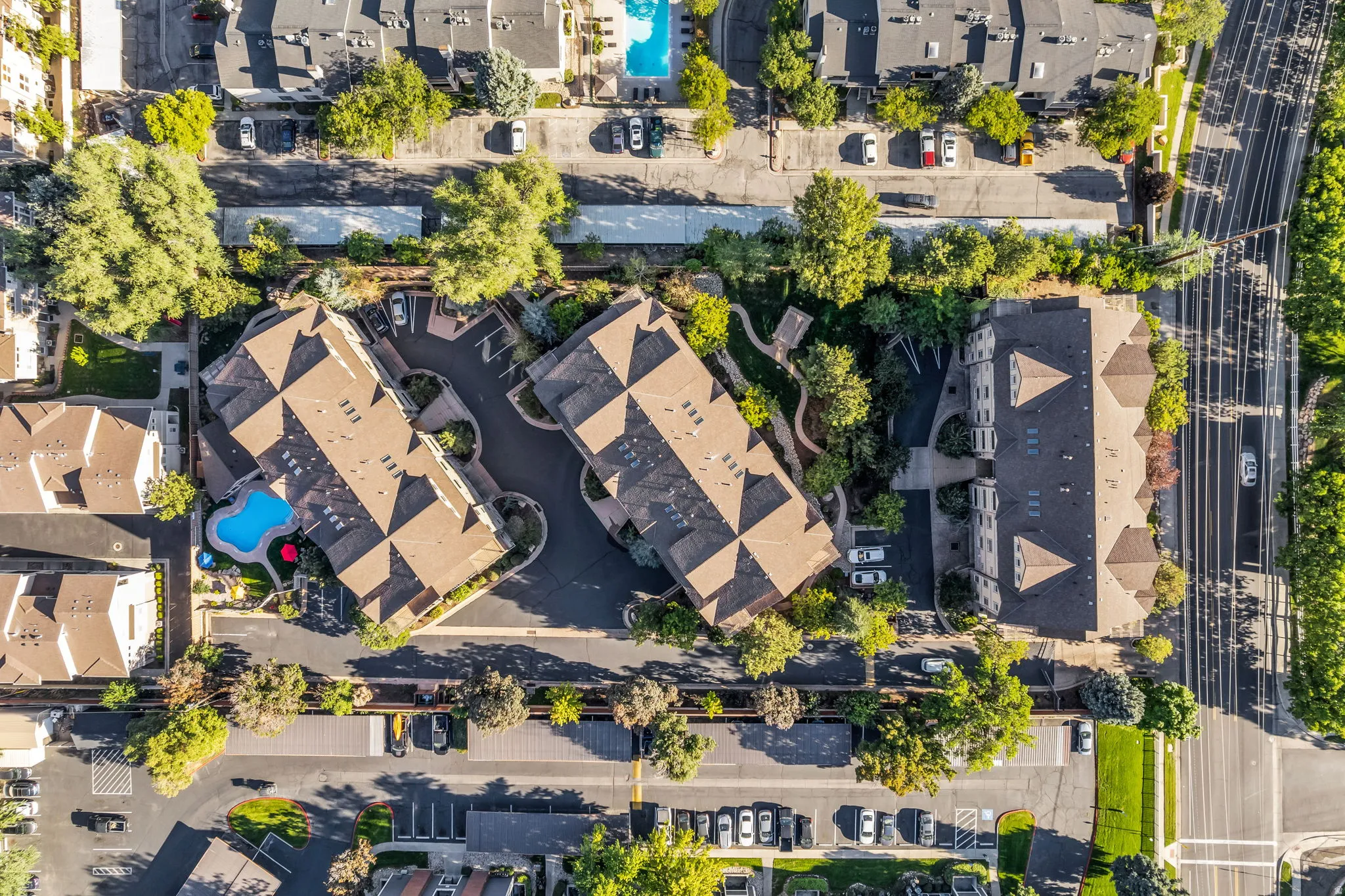 Development featuring multiple buildings with gabled roofs, a swimming pool, and dedicated parking areas
