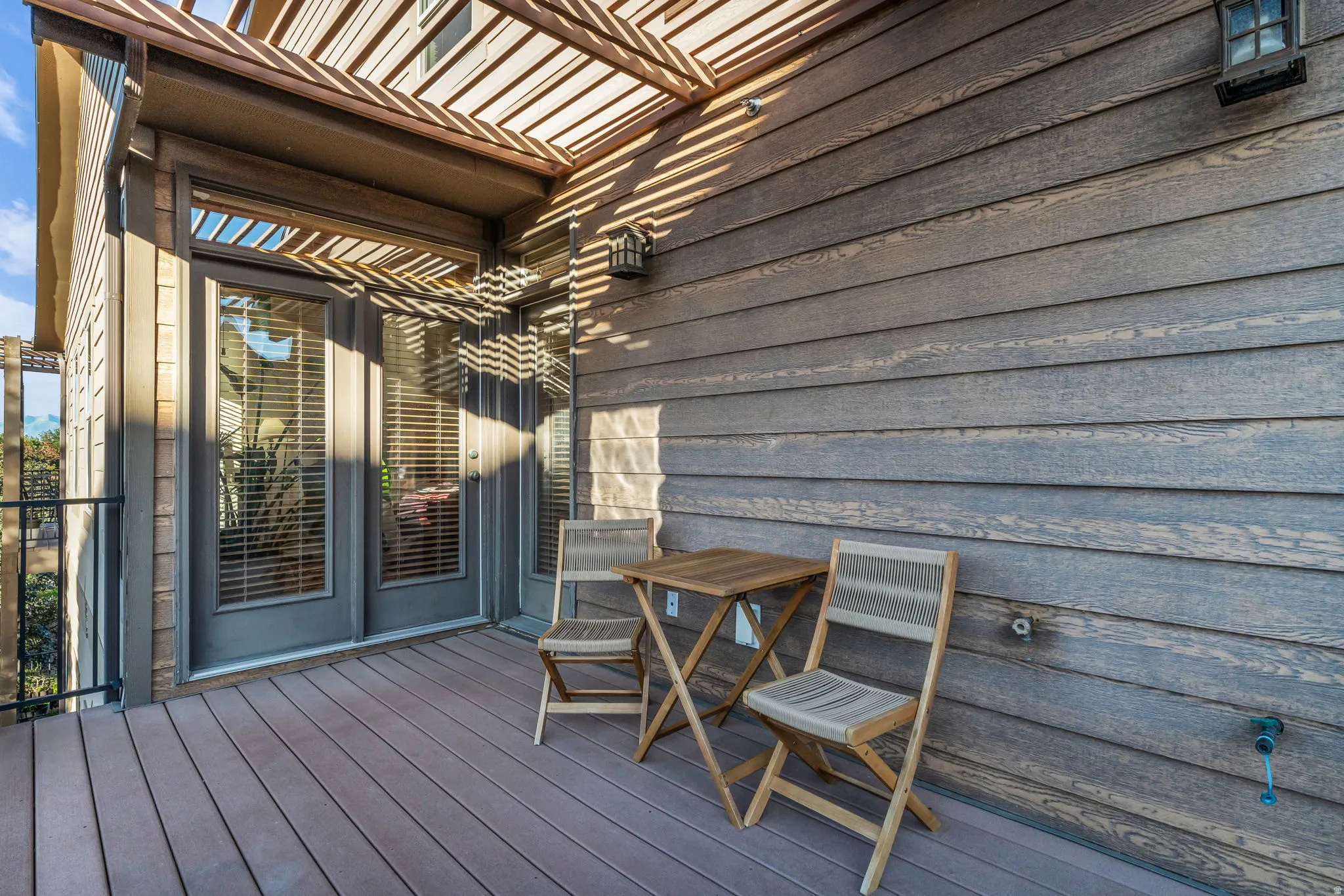 Deck access from bedroom and main level hall.  with composite flooring, wood-finish pergola, and double French doors
