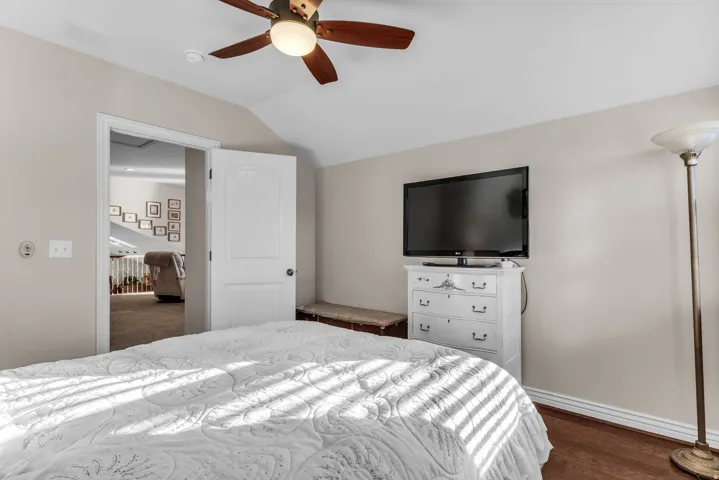 Hardwood-style flooring, ceiling fan with integrated lighting, and a neutral wall color