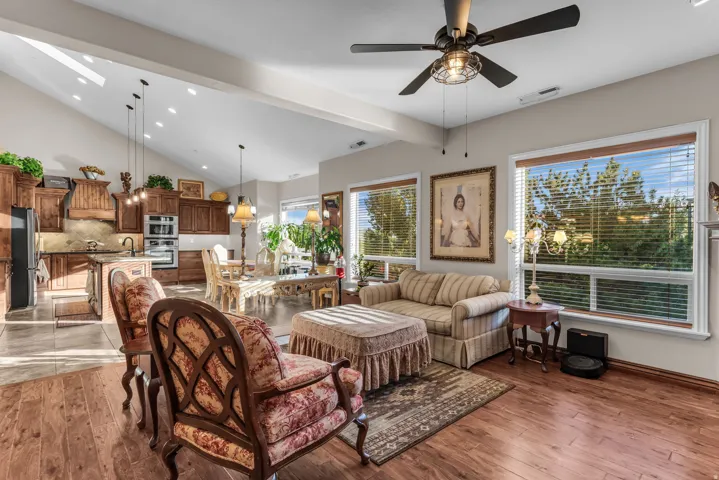 Vaulted ceiling with skylights, wood-finish flooring, built-in kitchen cabinetry, kitchen island, and ceiling fan