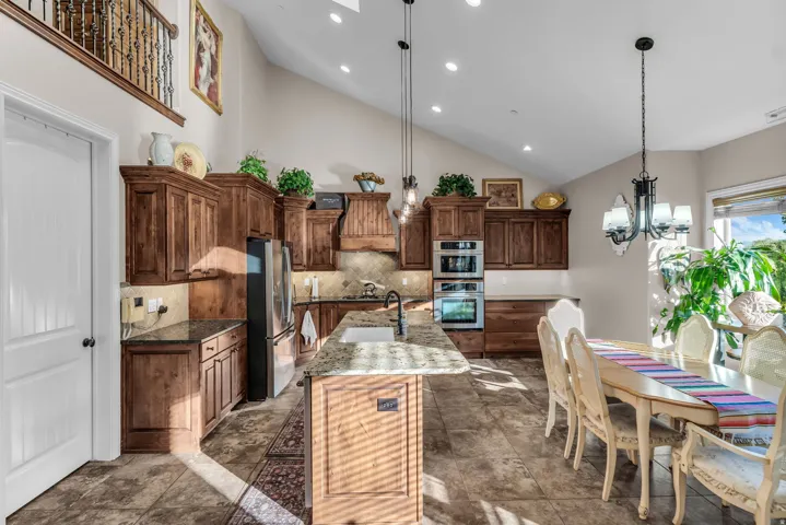 Open-concept kitchen and dining area featuring vaulted ceilings, recessed lighting, and tile flooring
