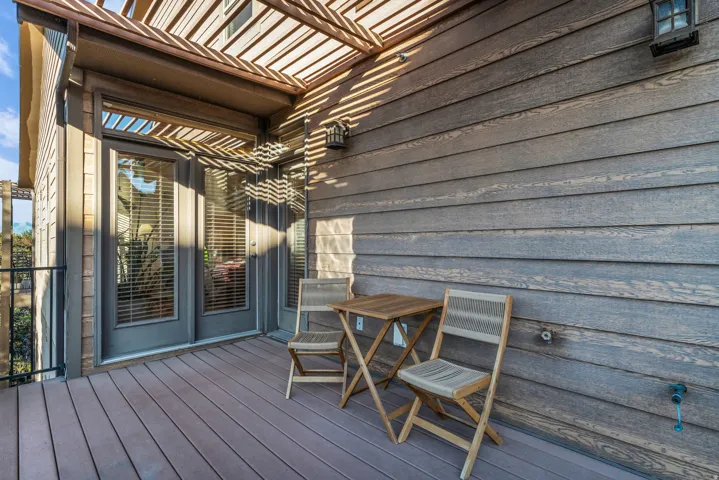 Deck access from bedroom and main level hall.  with composite flooring, wood-finish pergola, and double French doors