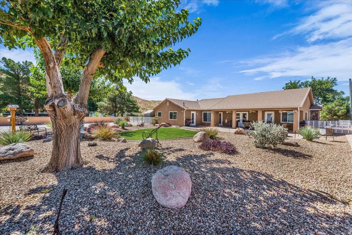 Expansive xeriscaped yard featuring mature trees, decorative boulders, and a manicured lawn area