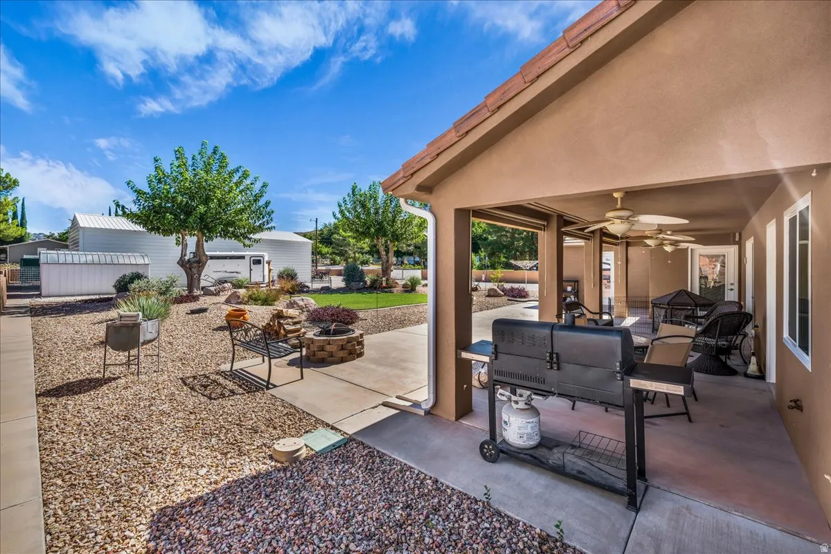 Covered patio with integrated outdoor kitchen featuring a built-in grill, stone countertop, and ambient lighting