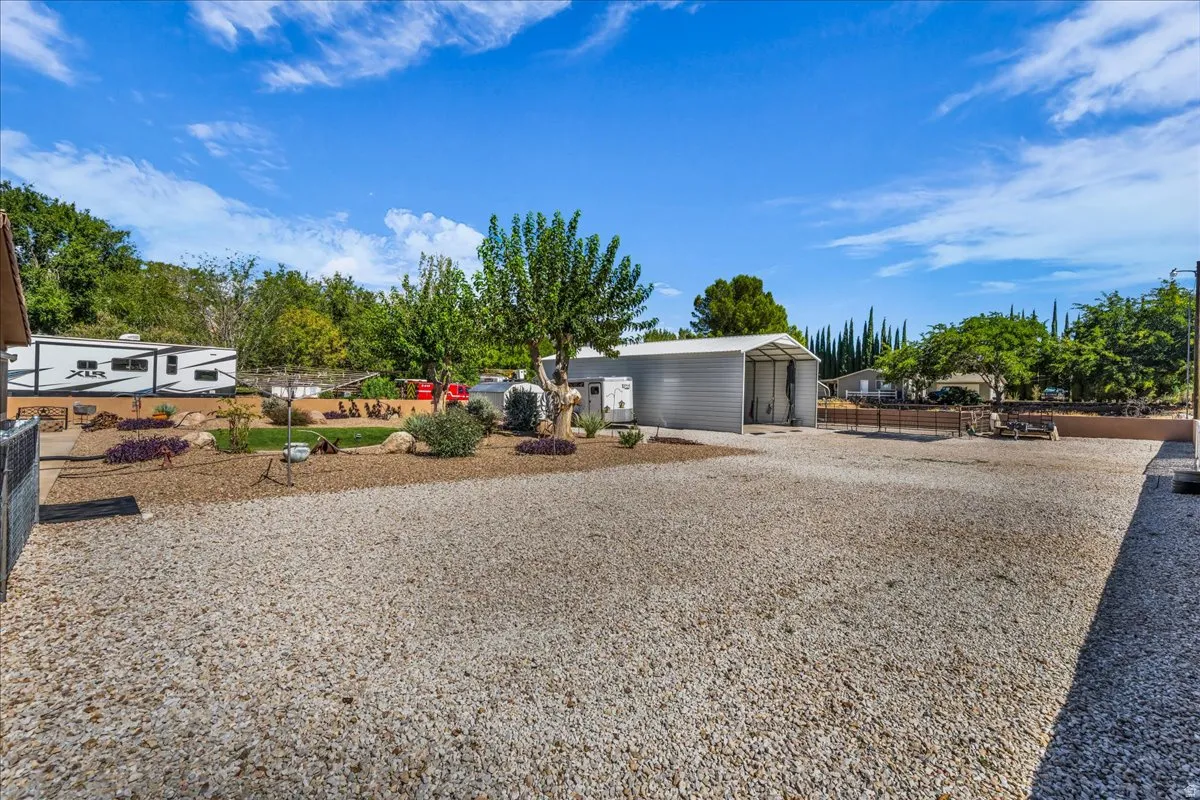 Expansive gravel yard with a dedicated storage building featuring a covered open bay