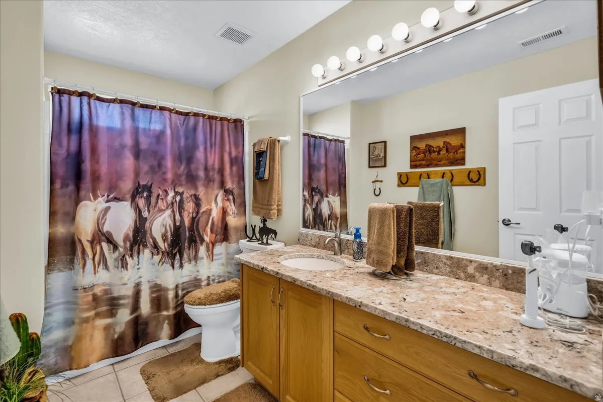 Single vanity with a light-toned stone countertop, integrated sink, and wood-finish cabinetry