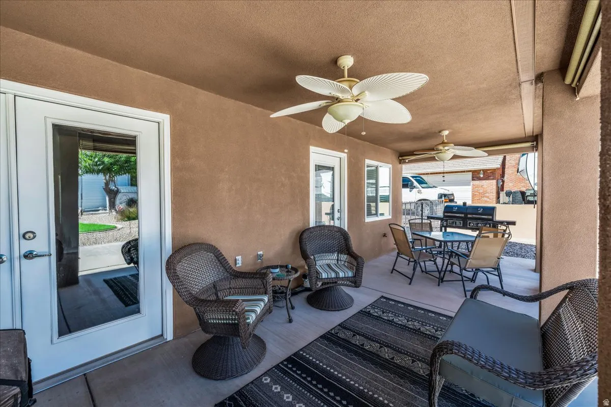 Covered patio with two ceiling fans, two exterior glass-paneled doors, and exterior lighting