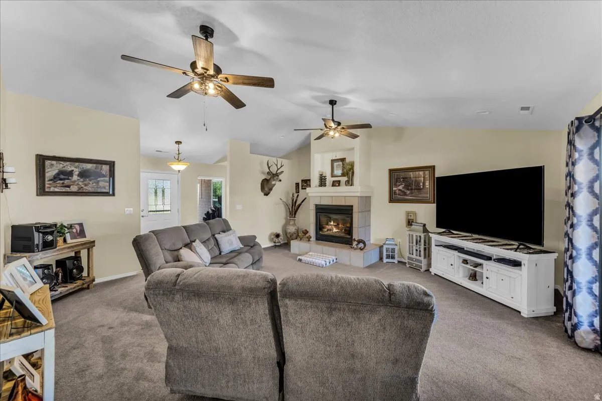 Vaulted ceilings with ceiling fans, fireplace with tile surround, recessed lighting, and a white paneled entry door with frosted glass inserts