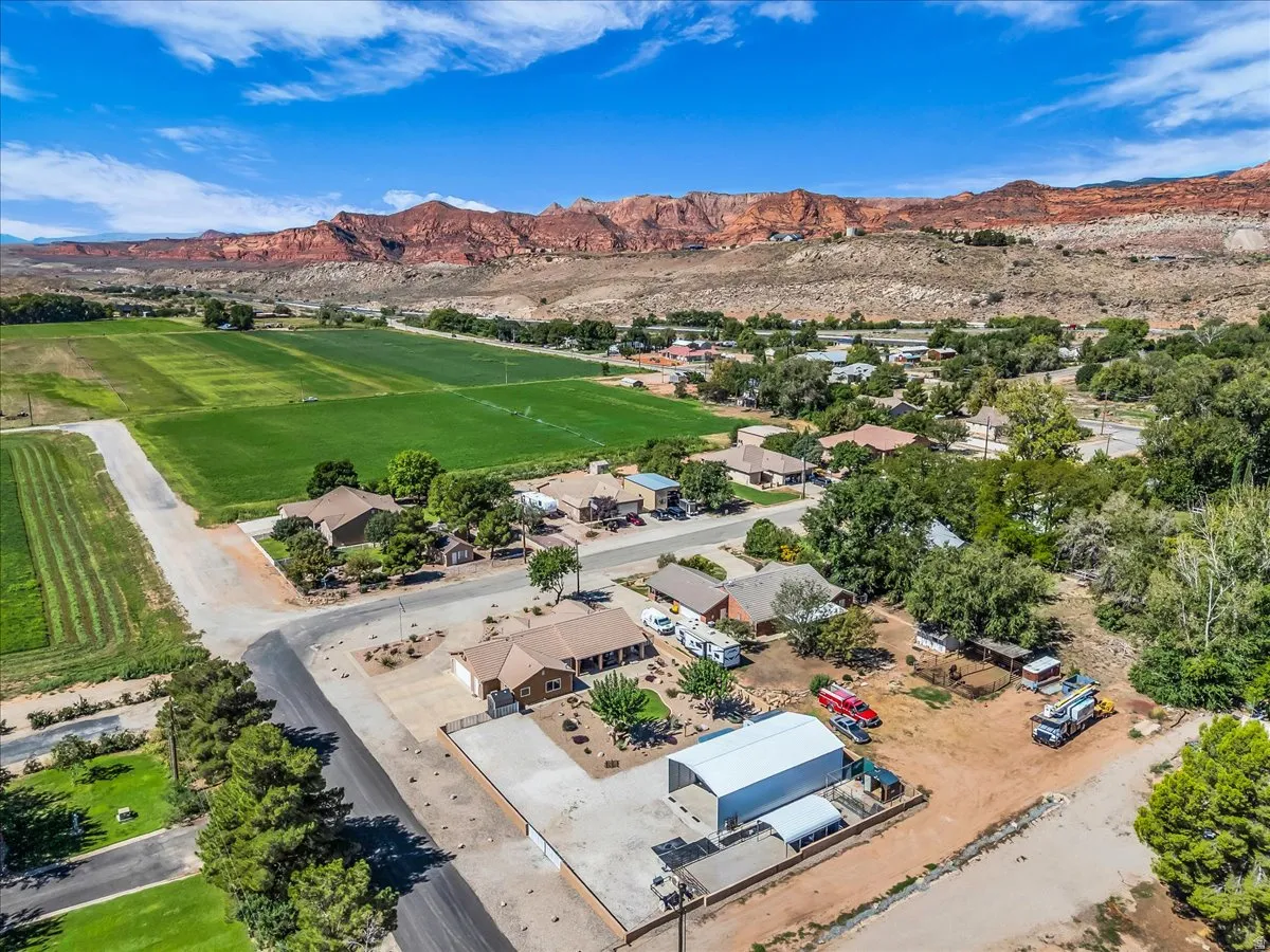 Expansive landscape featuring distant red rock formations and a green agricultural field