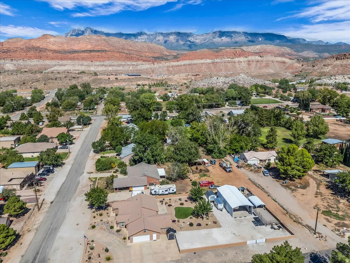 Mountain backdrop, residential street, large detached outbuilding, mature trees, expansive paved areas