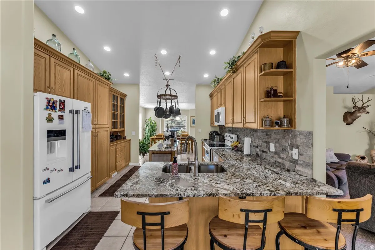 Kitchen featuring wood-finish cabinetry, granite countertops, tile backsplash, and recessed lighting