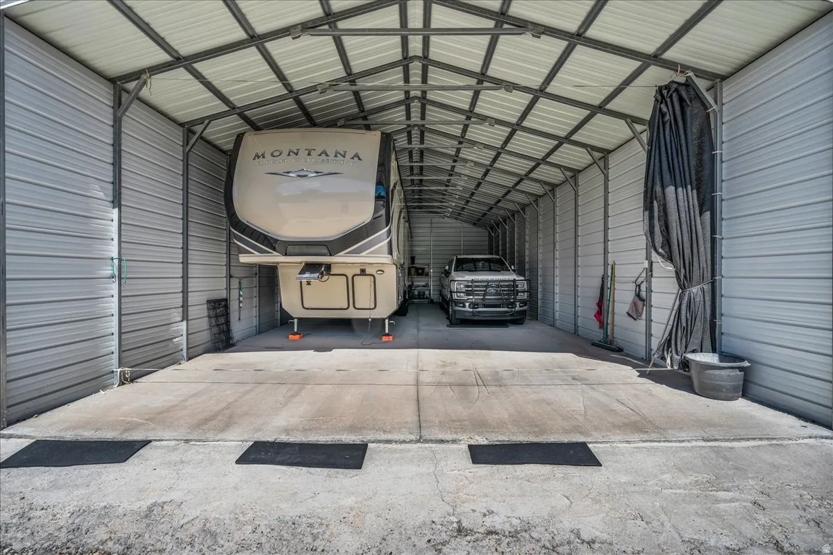 Expansive metal carport with a corrugated roof and concrete flooring