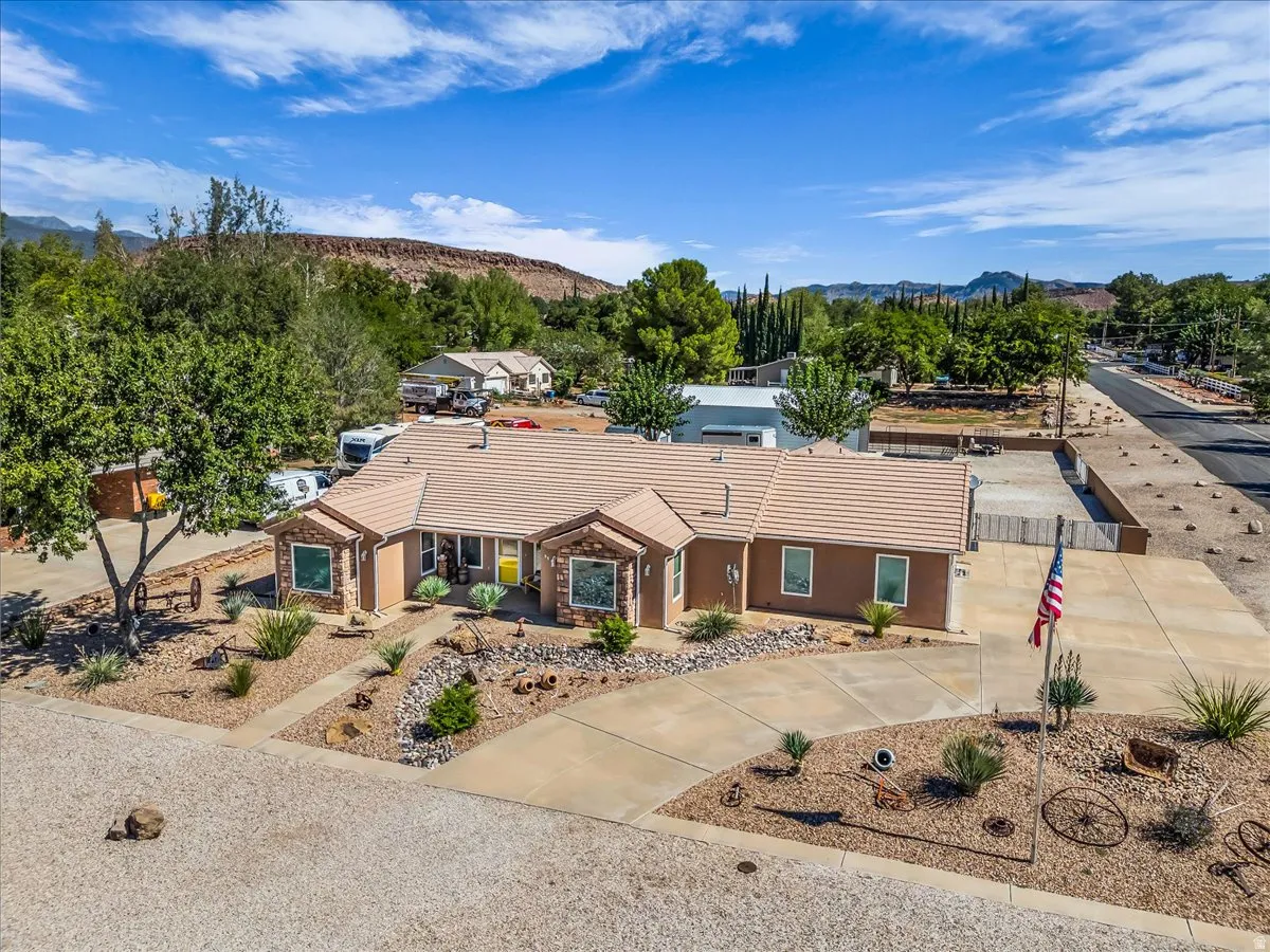 Single-story residence featuring a tile roof and a desert-inspired landscaped front yard with mature trees