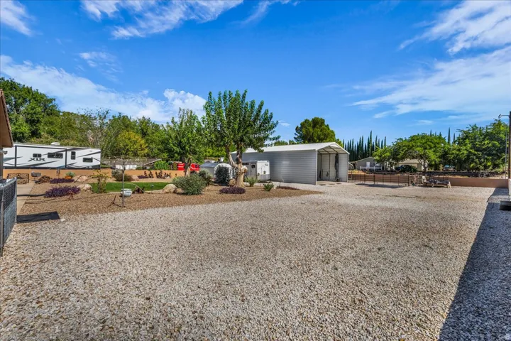 Expansive gravel yard with a dedicated storage building featuring a covered open bay