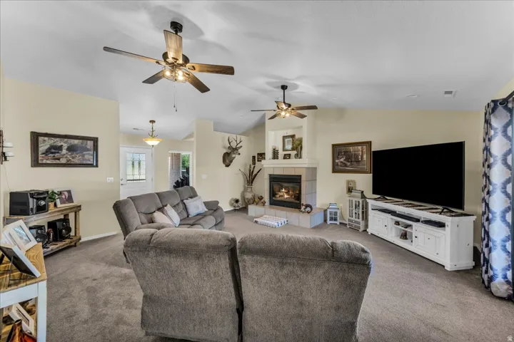 Vaulted ceilings with ceiling fans, fireplace with tile surround, recessed lighting, and a white paneled entry door with frosted glass inserts