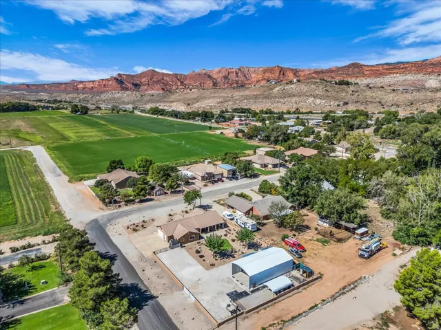 Expansive landscape featuring distant red rock formations and a green agricultural field