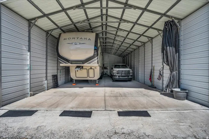 Expansive metal carport with a corrugated roof and concrete flooring