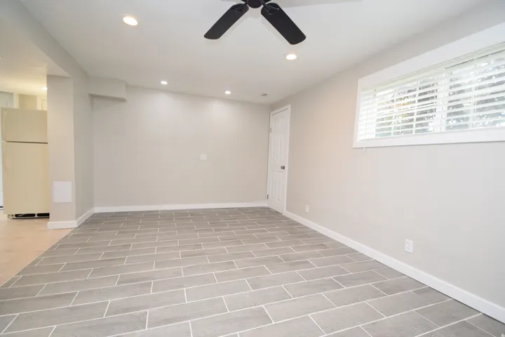 Grey plank tile flooring, recessed ceiling lighting, a ceiling fan, and a window with blinds