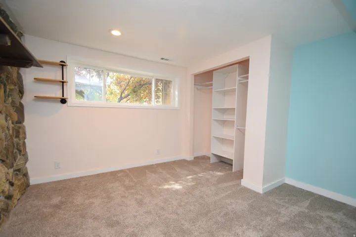 Recessed ceiling lighting, stone-clad wall accent, built-in shelving, window with exterior scenery, and carpeted flooring