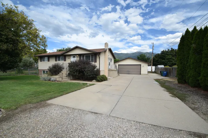 Split-level residence featuring a detached garage, a concrete driveway, and established landscaping
