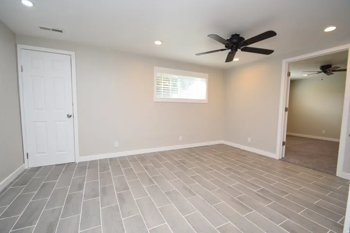 Recessed lighting, ceiling fan, window with horizontal blinds, plank-style flooring, and an interior door