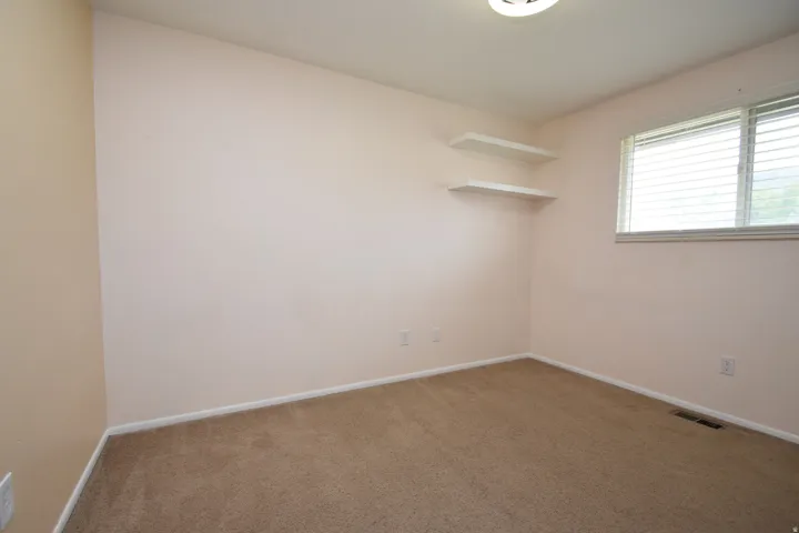 Room featuring carpeting, built-in shelving, a window with blinds, and a ceiling-mounted light fixture