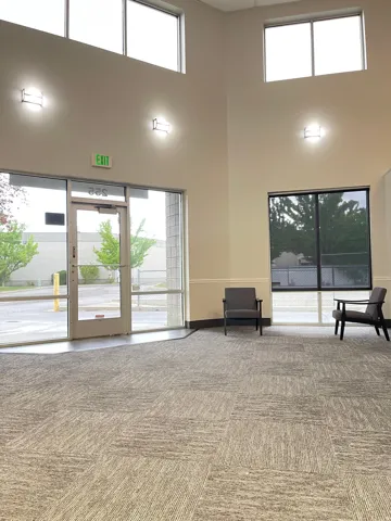 Expansive commercial space featuring a tall ceiling, upper transom windows, and full-height glass entry door