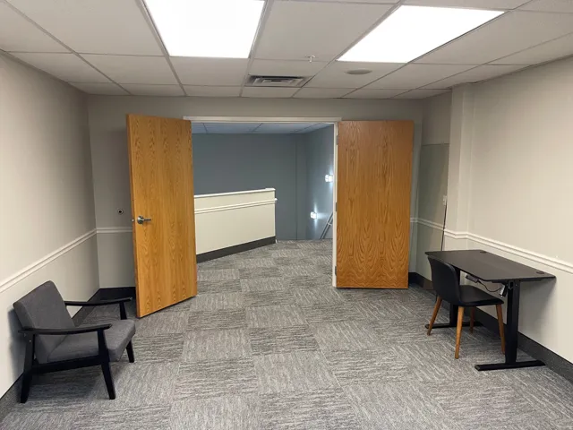 Wall-to-wall patterned carpeting, neutral wall finishes, recessed fluorescent lighting, and natural wood-finish doors