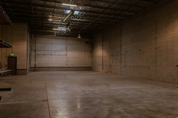 Concrete block walls, exposed structural ceiling, high bay lighting, overhead door, concrete flooring
