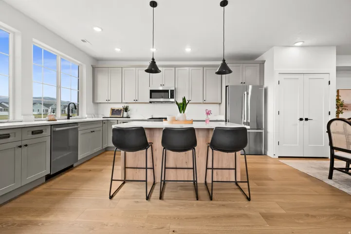 Kitchen featuring wood-finish flooring, a central island with countertop seating, stainless steel appliances, and large windows