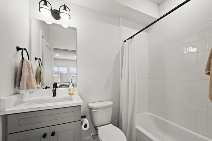 Vanity with gray cabinetry, white countertop, and matte black faucet
