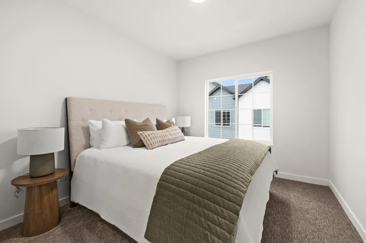 Bright secondary bedroom with neutral wall finishes, carpeted flooring, and natural light from glass sliding doors opening to exterior space
