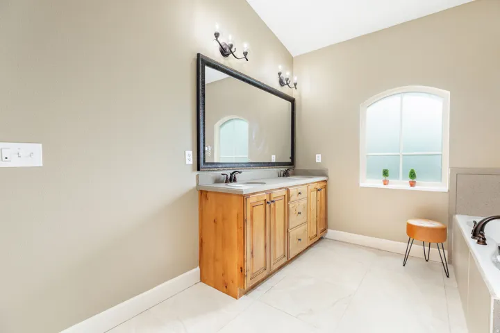 Dual vanity with wood-finish cabinetry, light-toned countertop, and integrated sinks