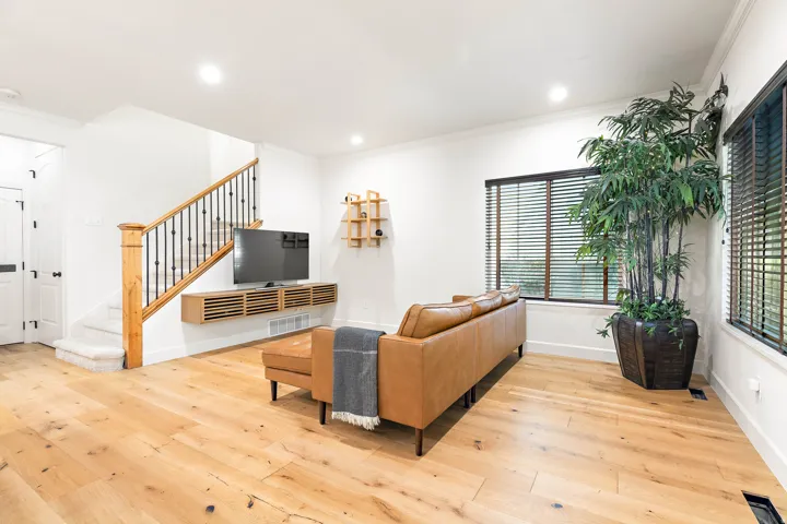 Wide-plank wood-finish flooring, white walls, recessed lighting, and a staircase with wrought iron balusters