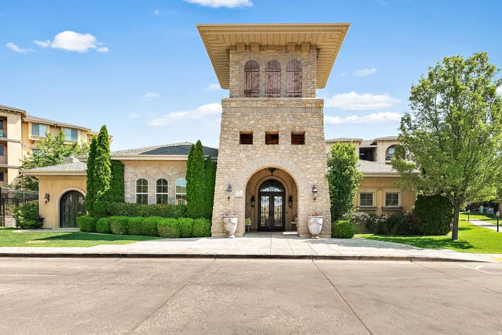 Stone facade building with an arched entryway, detailed double doors, and a prominent central tower featuring decorative window shutters