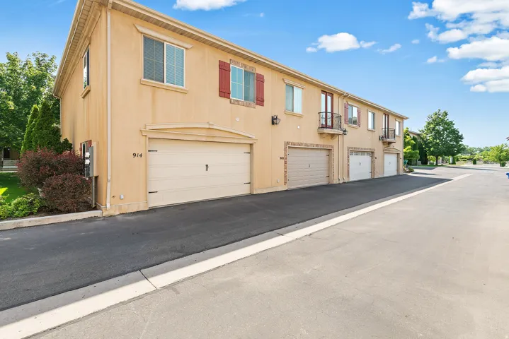 Stucco exterior with multiple garage bays, individual balconies with wrought iron railings, and red decorative window shutters
