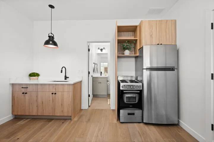 Full kitchen with stainless steel refrigerator, compact range, wood-finish cabinetry, and white countertops