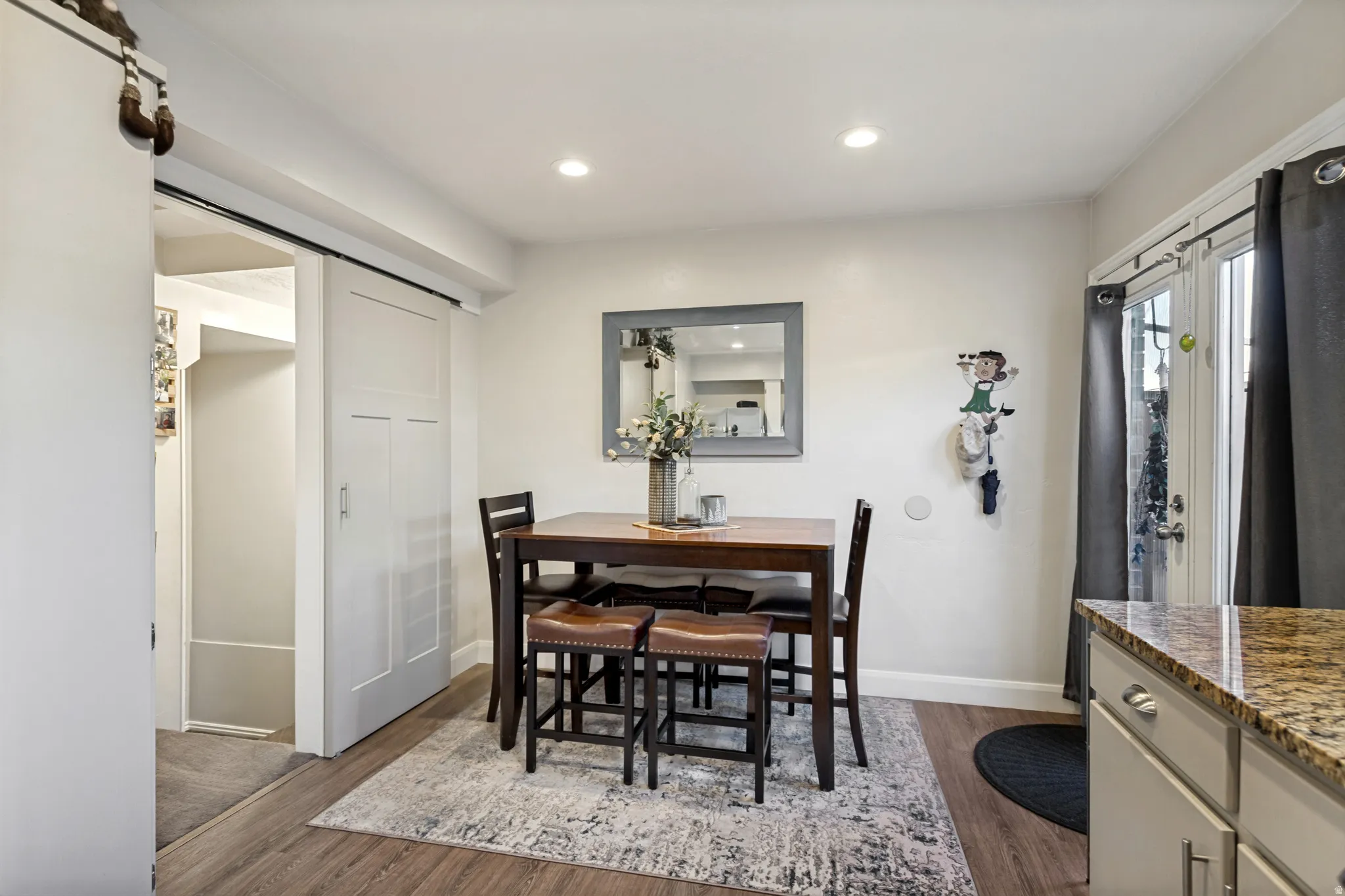 Wood-finish flooring, recessed ceiling lighting, barn-style interior door, and double French doors to the exterior