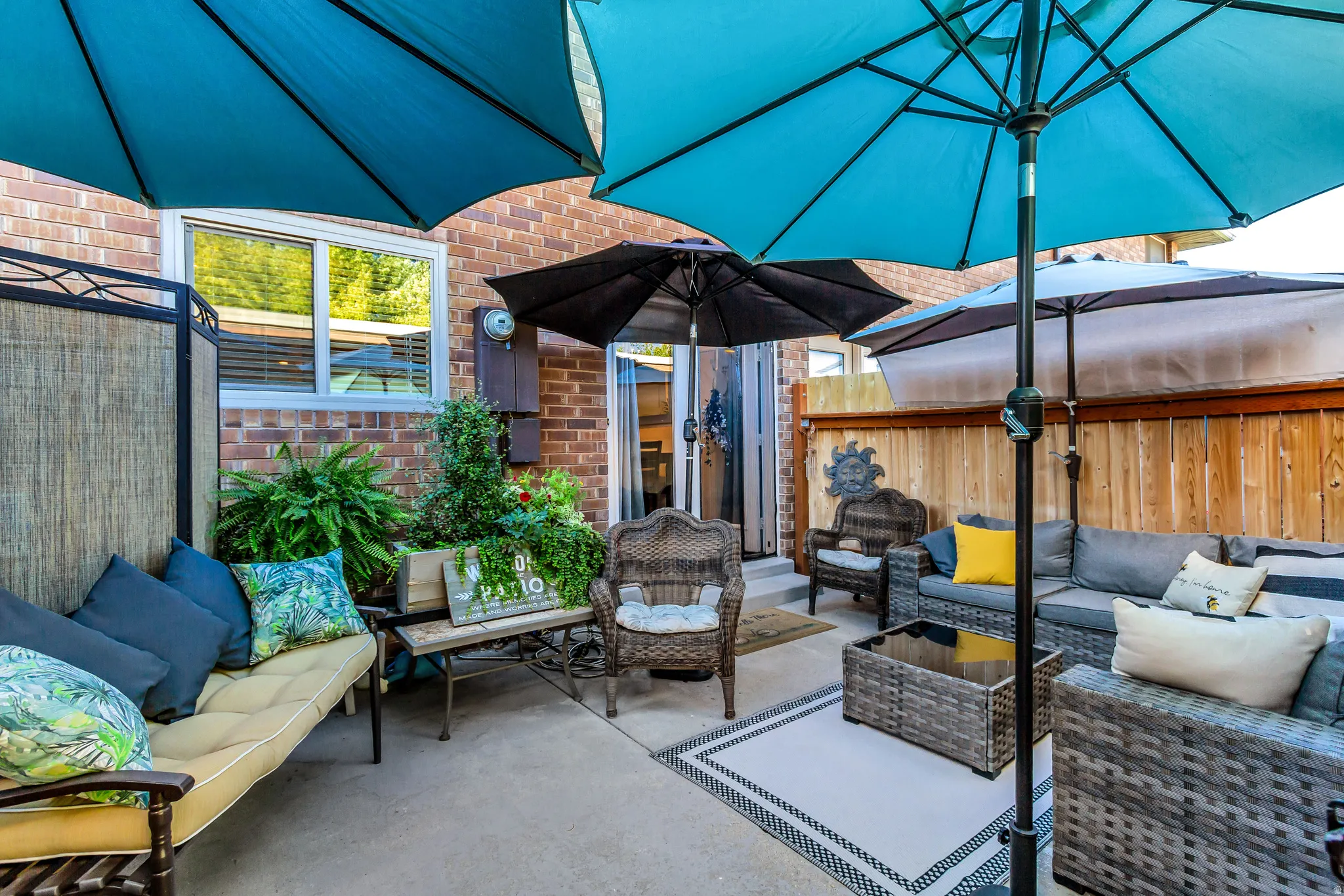 Concrete patio with a brick exterior, wood fence, and privacy screen