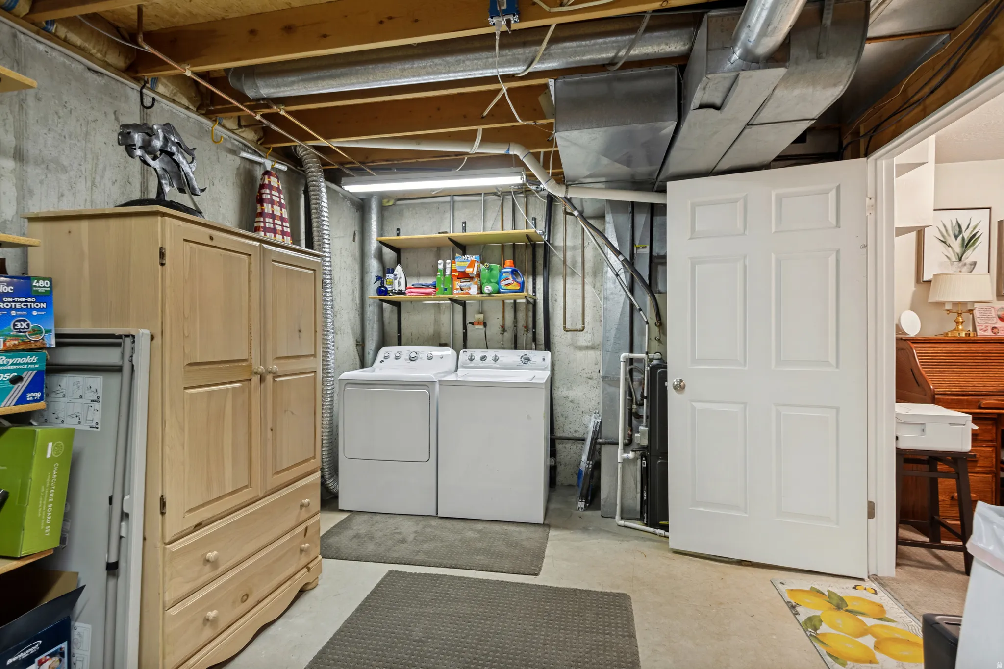 Laundry area featuring washer and dryer, exposed ceiling joists, and concrete walls