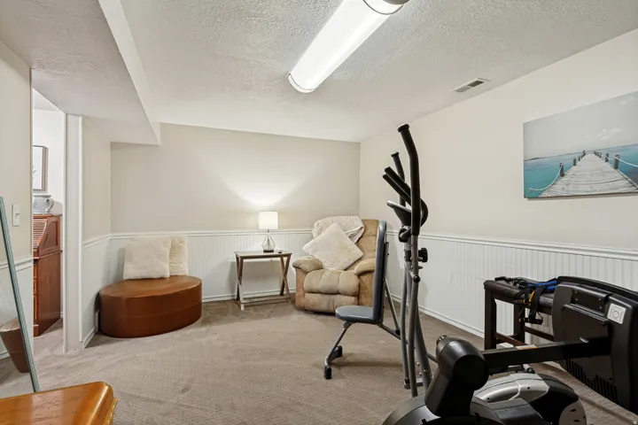 Recessed ceiling with an overhead fluorescent light fixture, carpeted flooring, and white wainscoting
