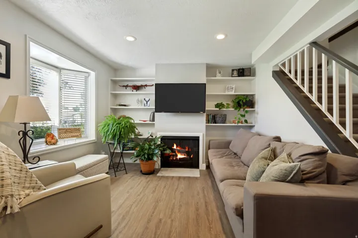 Bay window, wood-finish flooring, built-in shelving, fireplace, staircase with carpeted treads