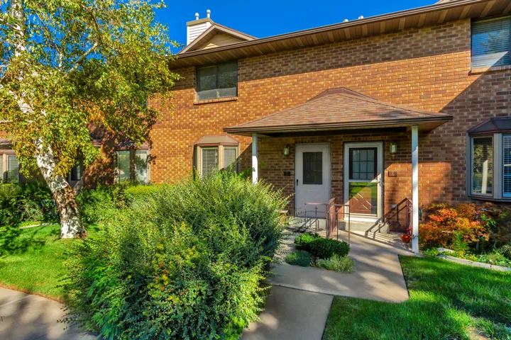 Brick facade exterior with a covered entry, bay window, concrete walkway, and established landscaping