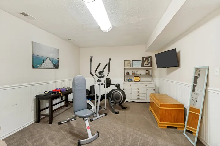 Carpeted room with wainscoting and a wall-mounted television